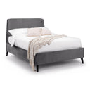 Gray upholstered bed with white bedding and a beige blanket on a white background