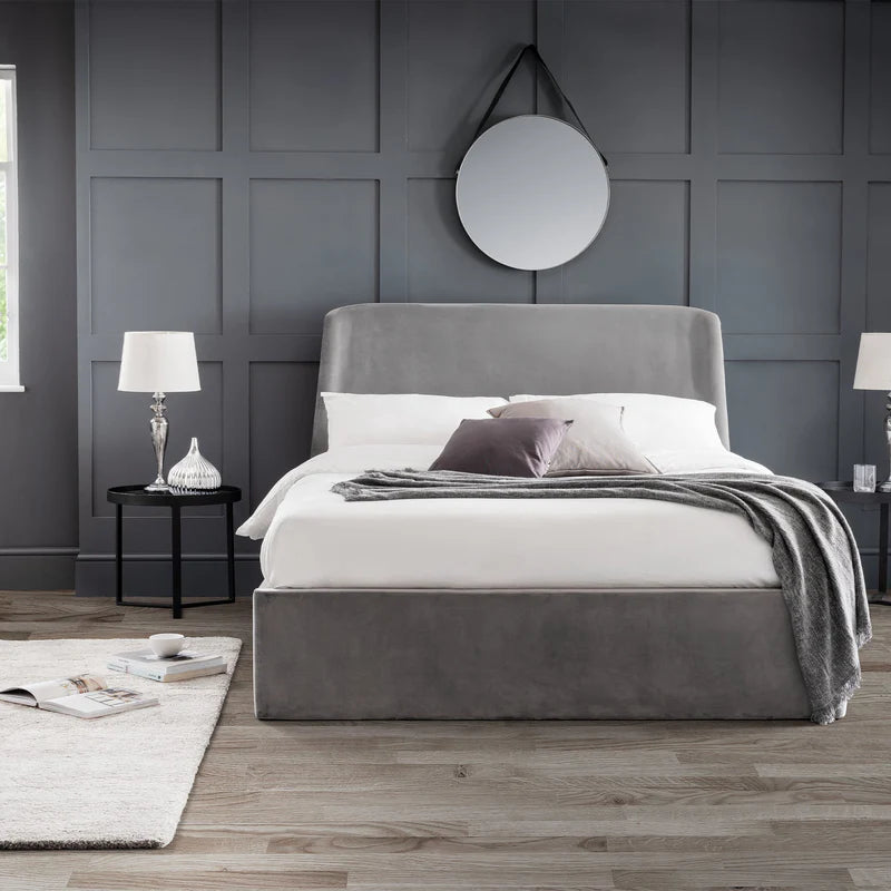 Gray upholstered bed with white bedding and gray blanket on a white background