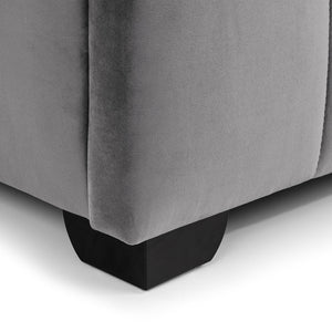 Gray upholstered corner of a bed with black legs on a white background