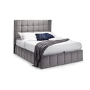 Gray upholstered bed with white bedding and a dark blue blanket on a white background