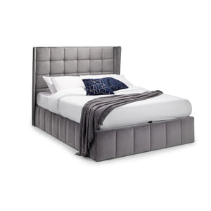 Gray upholstered bed with white bedding and a dark blue blanket on a white background