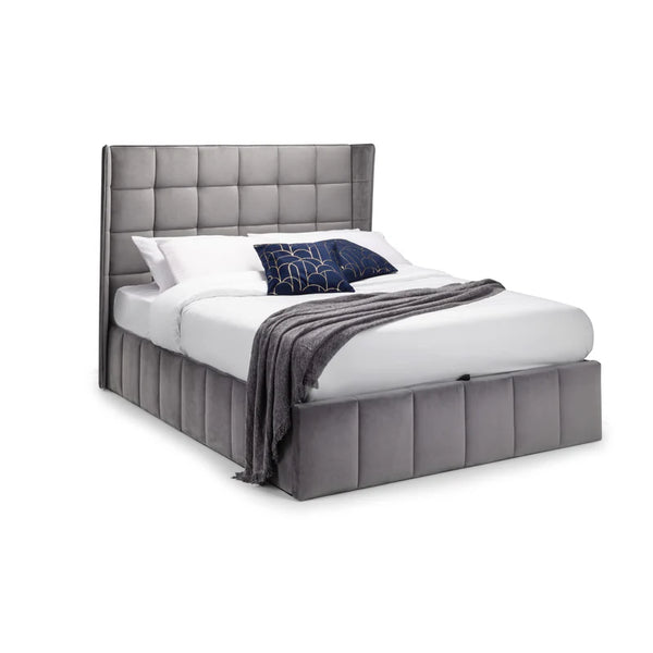 Gray upholstered bed with white bedding and a dark blue blanket on a white background