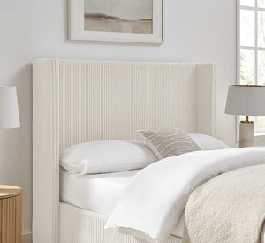 Neatly made bed with a textured headboard in a bright bedroom.