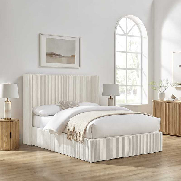 White bed in a bright bedroom with wooden furniture and decor.