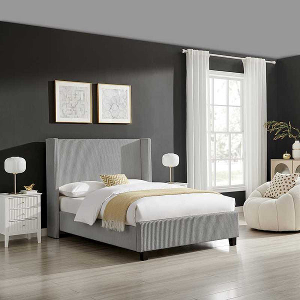 Modern bedroom with gray upholstered bed, white nightstands, and a window with white curtains.