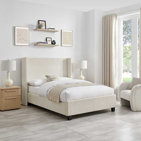 Beige upholstered bed in a modern bedroom with light wood nightstands and lamps.