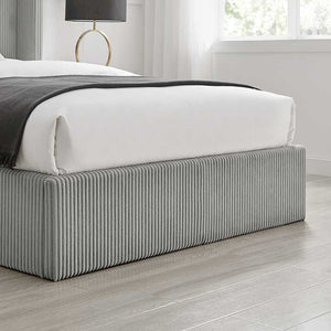 Gray upholstered bed with white bedding in a modern bedroom setting.