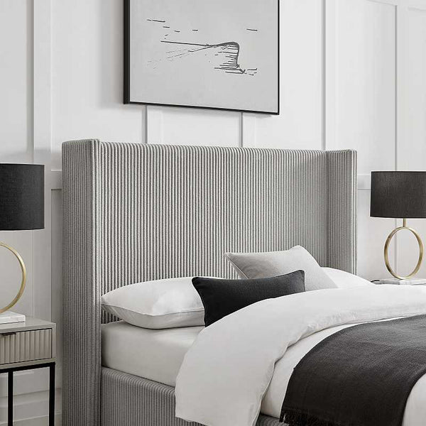Modern bedroom with a gray upholstered bed, white bedding, and black and gold lamps.