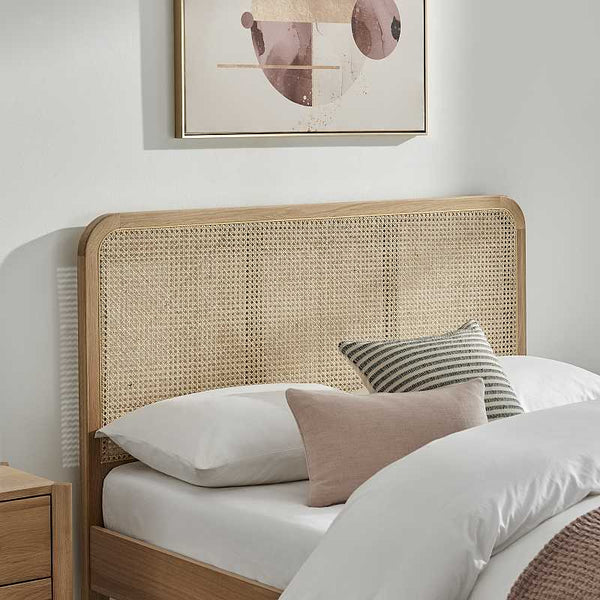 Bedroom with a wicker headboard and decorative pillows on a bed.