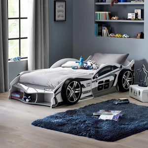 Children's room with a race car bed, toys, and a blue rug.