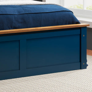 Blue bed with wooden headboard in a room with a window