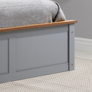 Gray bed frame with wooden headboard against a gray wall.
