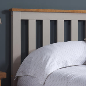 Gray bed with wooden headboard against a dark blue wall