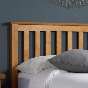Wooden headboard with pillows on a bed against a dark gray wall.