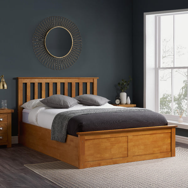 Wooden bed in a bedroom with dark walls and a large window.