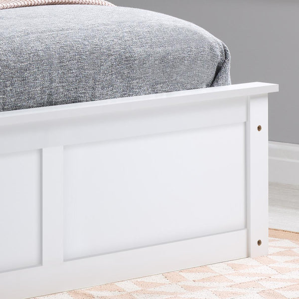 White wooden bed frame with a gray bedding against a gray wall.