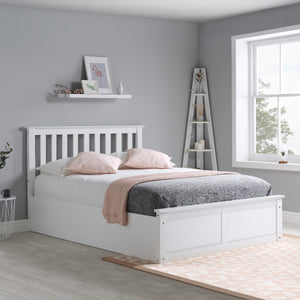 White bed in a bedroom with gray walls and a window.