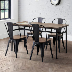 Dining area with wooden table and black metal chairs on a herringbone wood floor.