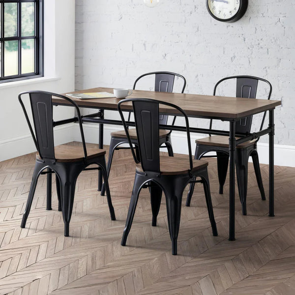 Dining area with wooden table and black metal chairs on a herringbone wood floor.