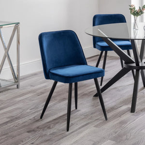 Blue velvet chair in a modern interior setting with a glass table.