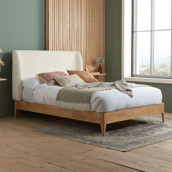 Wooden bed with white bedding and pillows in a room with a window and wooden floor.