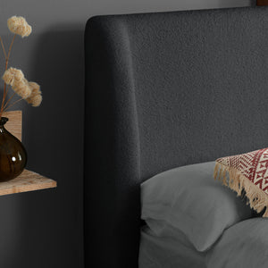 Dark upholstered headboard with a vase and decorative elements on a shelf.