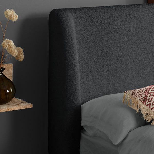 Dark upholstered headboard with a vase and decorative elements on a shelf.