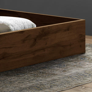 Wooden bed frame on a grey rug with a green wall