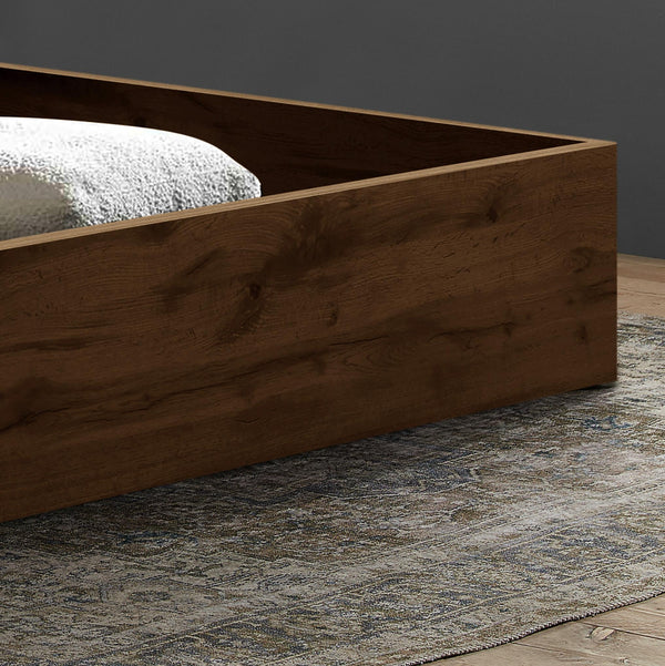 Wooden bed frame on a grey rug with a green wall