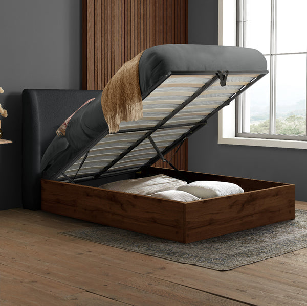 Wooden bed frame with open headboard in a room with a window and curtains.