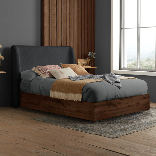 Bedroom with a wooden bed frame and upholstered headboard, featuring pillows and blankets.