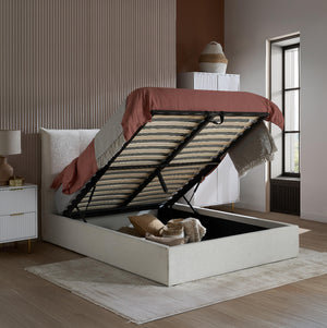 Modern bedroom with a white bed frame with storage compartments, striped bedding, and a red blanket.