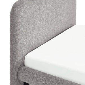 Grey upholstered bed with a white mattress on a plain background