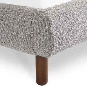 Gray textured bedspread on a bed with wooden bedpost against a white background