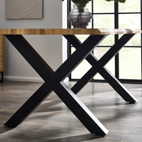 Dining table with black X-shaped legs in a room with large windows.
