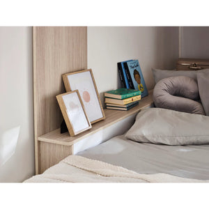 Bedroom setup with a wooden headboard shelf, books, and framed pictures.