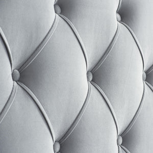 Close-up of a tufted gray upholstered headboard