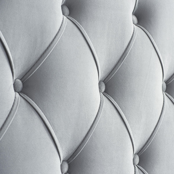 Close-up of a tufted gray upholstered headboard