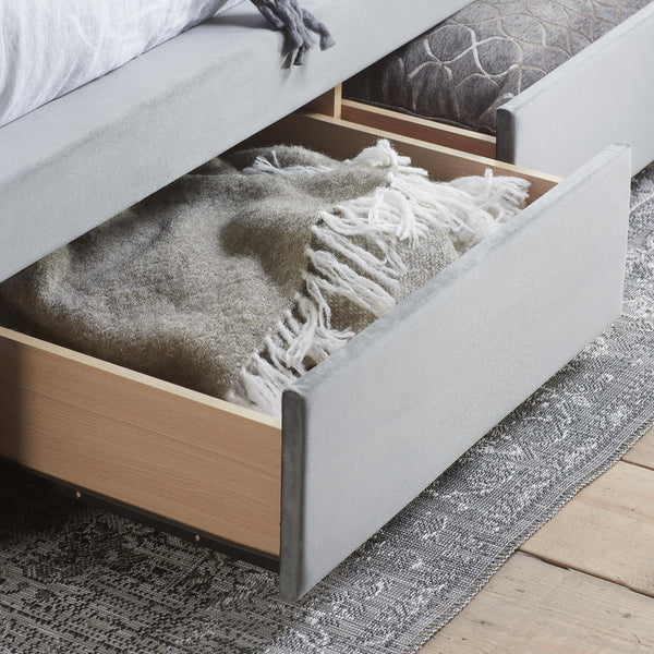 Gray and white plaid blanket in an open drawer of a bed with wooden frame.