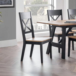 Dining table with black chairs in a room with large windows.