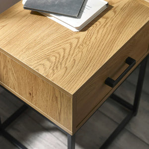 Wooden desk with black metal legs and handles on a gray floor.