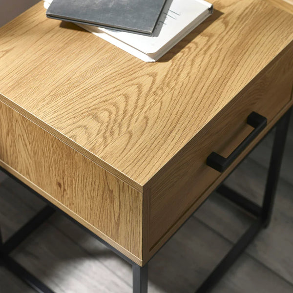 Wooden desk with black metal legs and handles on a gray floor.