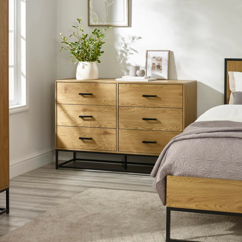 Wooden dresser with four drawers and black metal legs on a white background