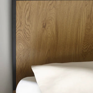 Wooden headboard with a white pillow against a neutral wall