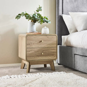 Wooden nightstand with decorative items next to a bed in a bedroom setting