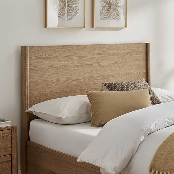 Wooden headboard with pillows on a bed in a bedroom setting
