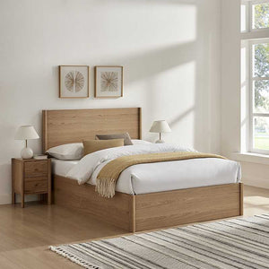 Wooden bed with white bedding and a striped rug in a bright bedroom.