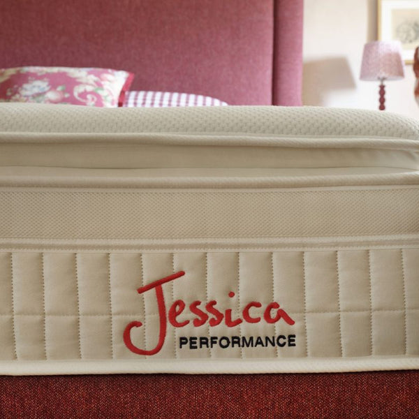 Beige mattress with 'Jessica Performance' branding in a bedroom setting.