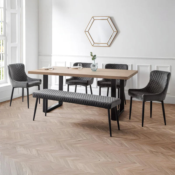 Dining room with wooden table, gray chairs, and bench on a wooden floor.