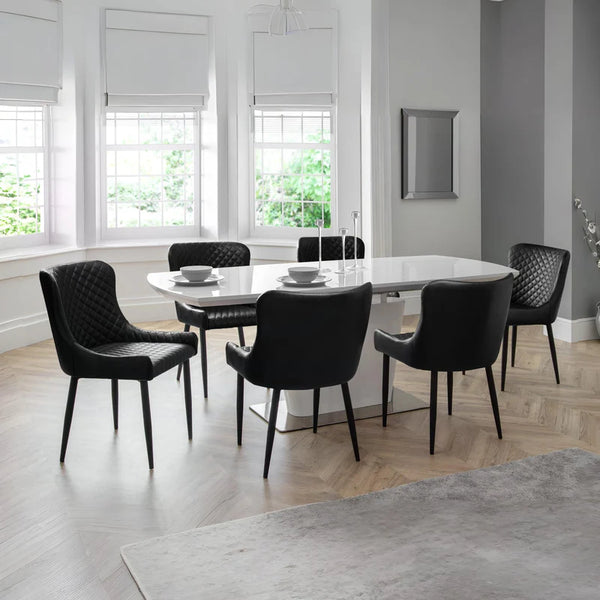 Modern dining room with a round white table and black chairs.